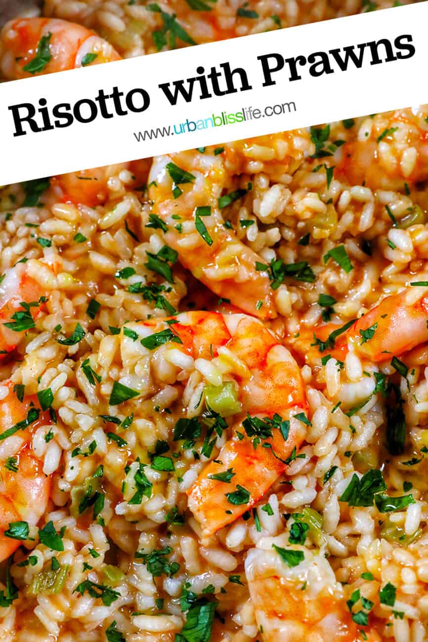 closeup of risotto with prawns and herbs in a stainless steel pan.