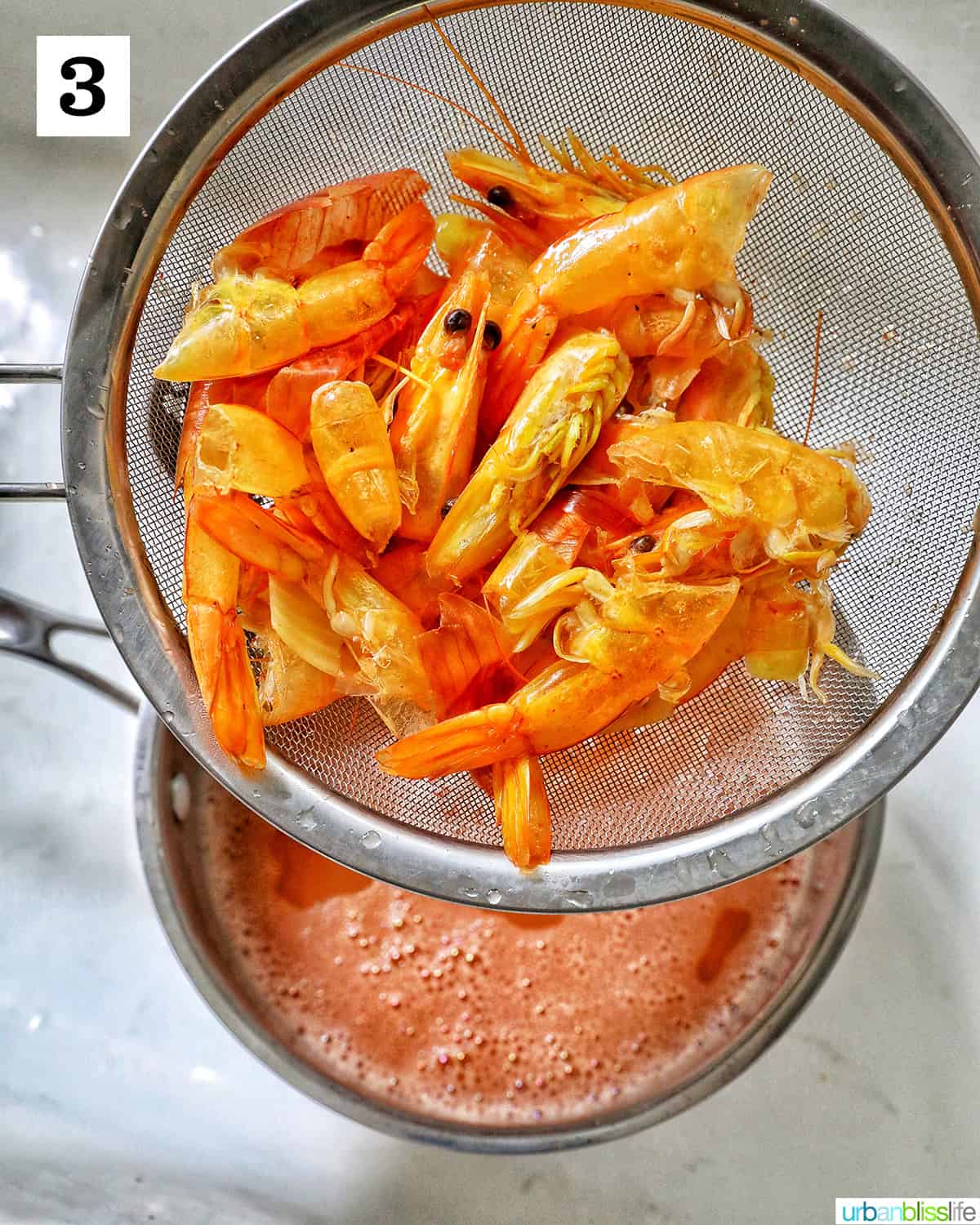 strainer draining the prawn stock into a bowl underneath.
