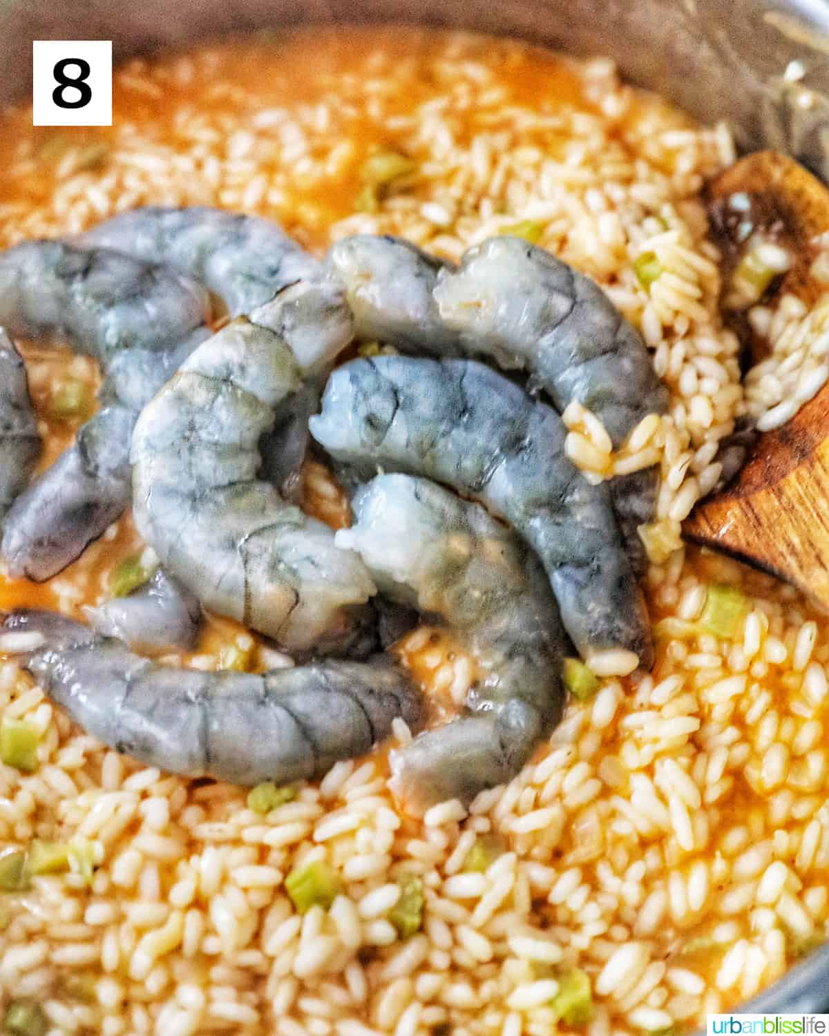 raw prawns added to the risotto in a pan.