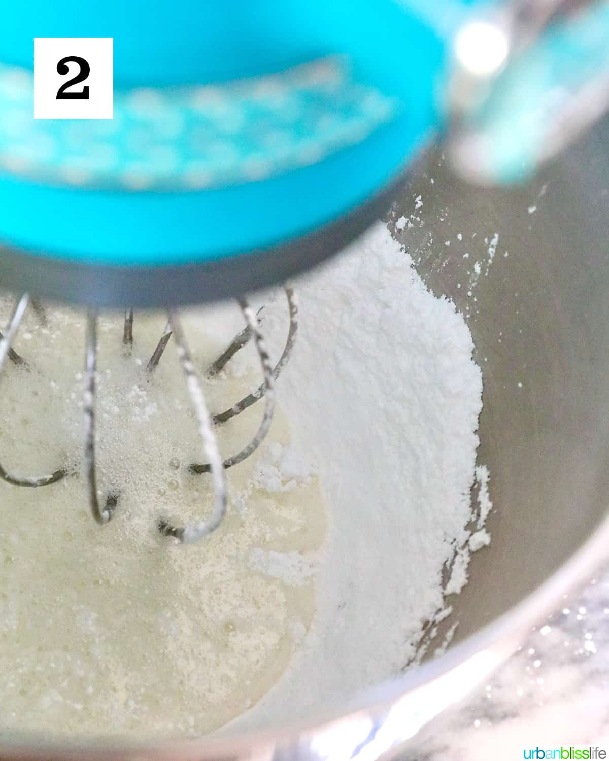 stand mixer with royal icing ingredients in the bowl mixing.