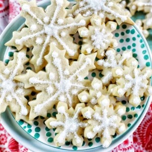 plate full of snowflake sugar cookies decorated with royal icing and decorator sugar.