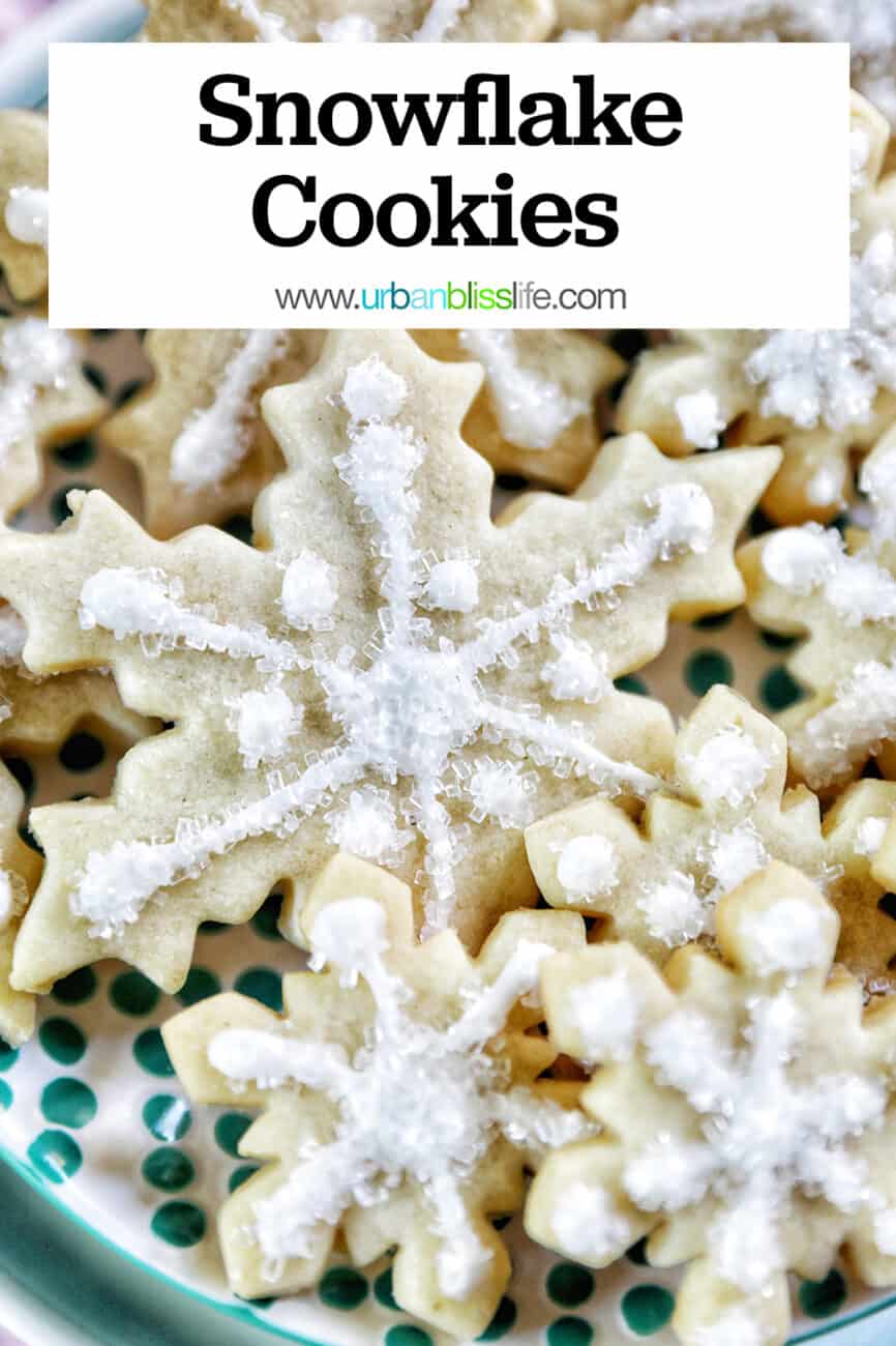 plate full of snowflake sugar cookies decorated with royal icing and decorator sugar.