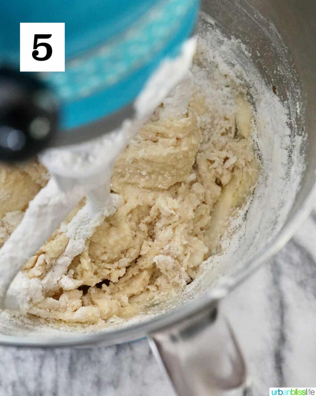 adding dry ingredients to wet ingredients of cookie batter in a stand mixer.