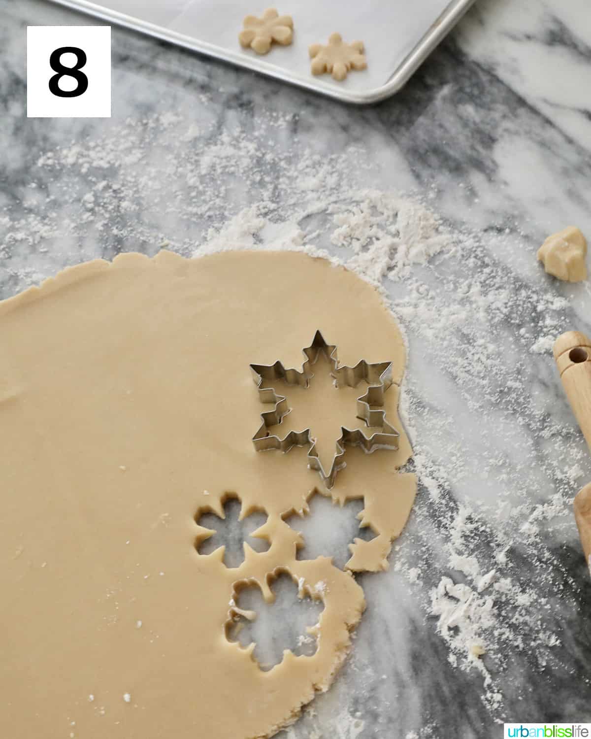 snowflake cookie cutters cutting out shapes from cookie dough.