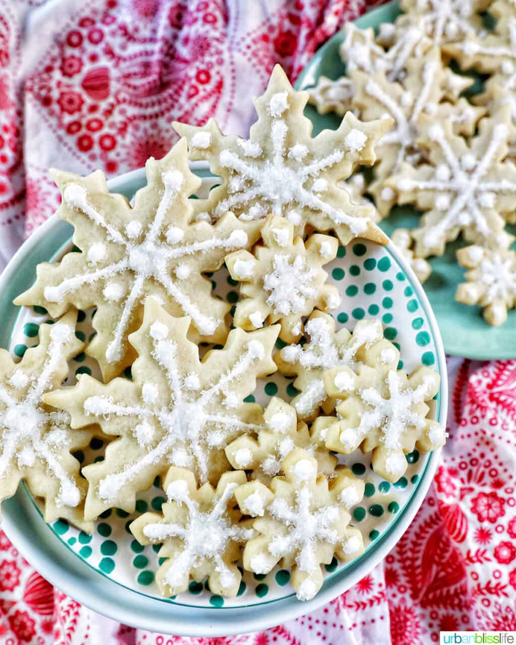 plate full of snowflake sugar cookies decorated with royal icing and decorator sugar.