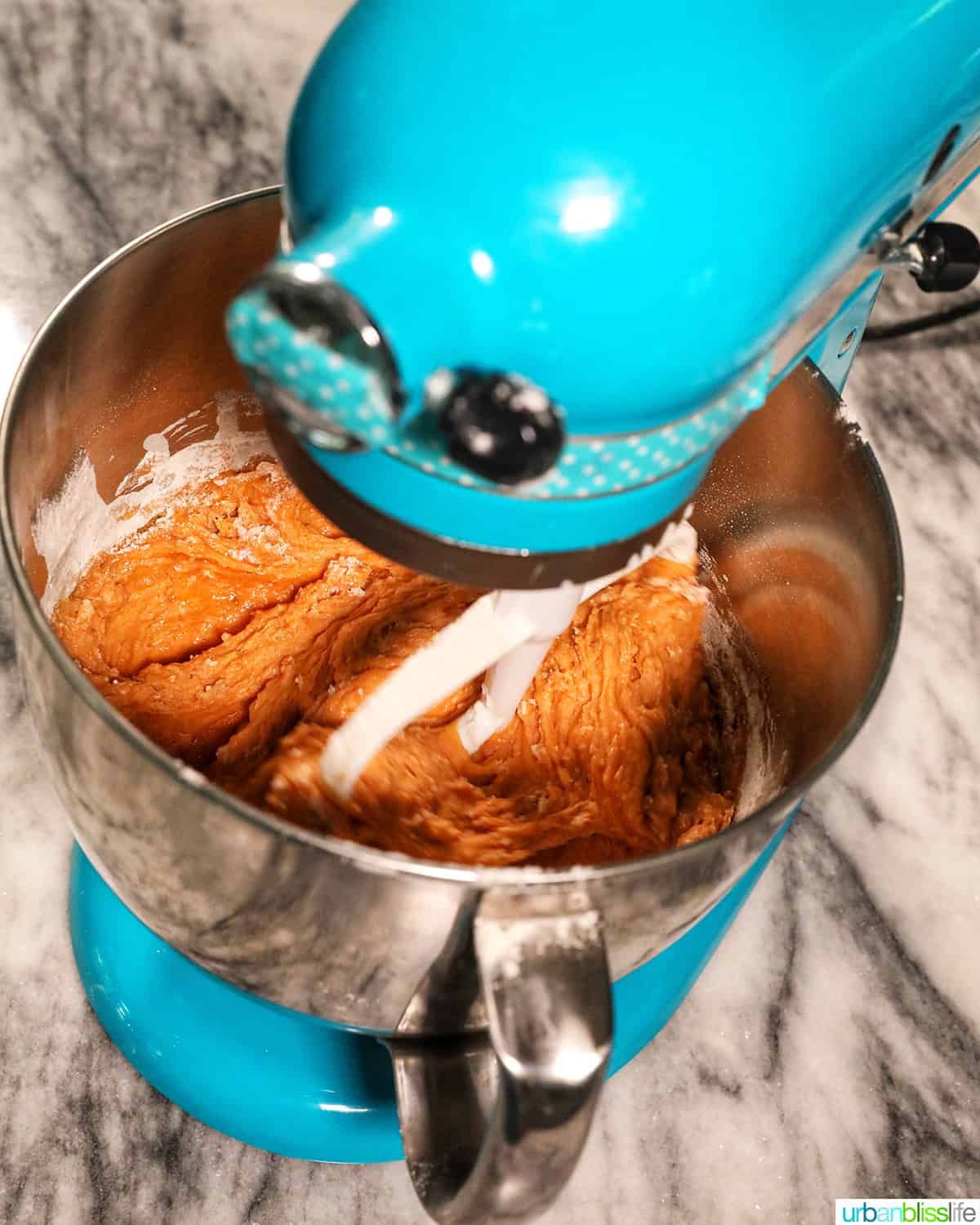 blue stand mixer with pumpkin banana muffin batter inside.