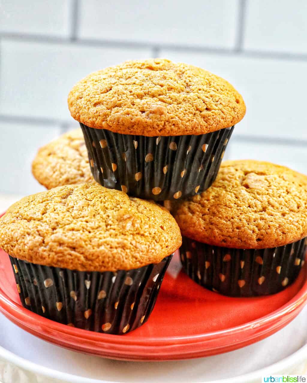 pumpkin banana muffins stacked on an orange plate.