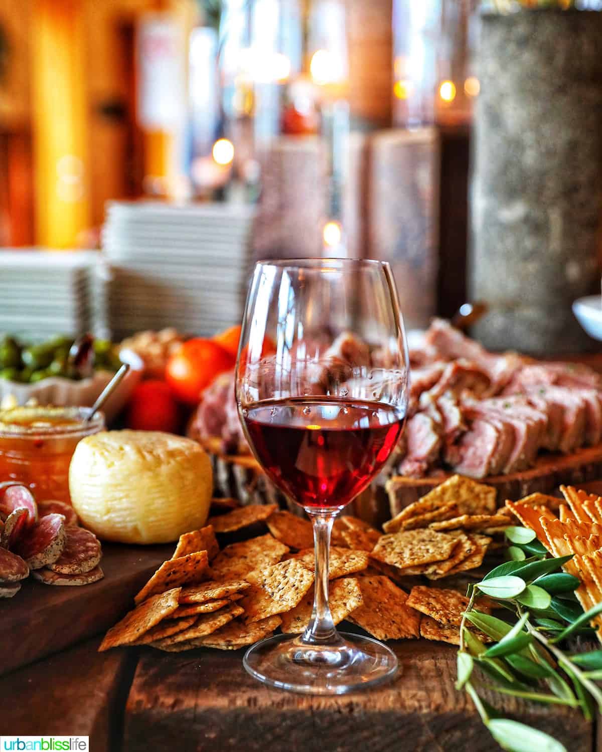 glass of red wine on a charcuterie board with meats, cheeses, crackers.