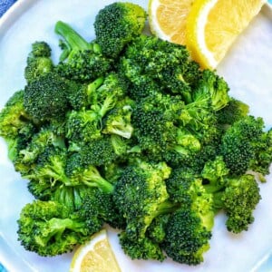 pressure cooked broccoli in a plate with lemon wedges.