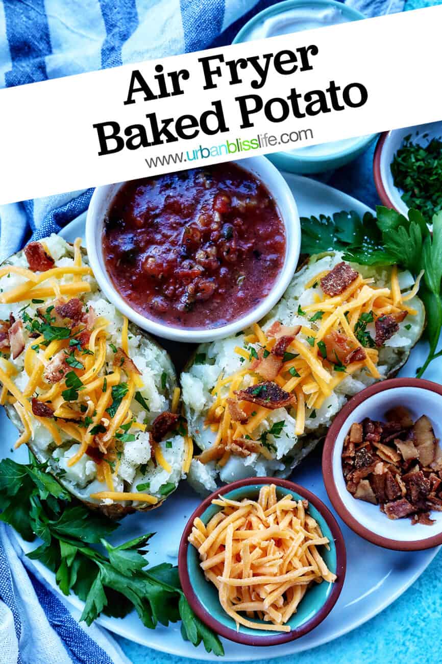 Loaded ninja foodi baked potato with title text overlay and sides of sour cream, cheddar cheese, parsley, and bacon.