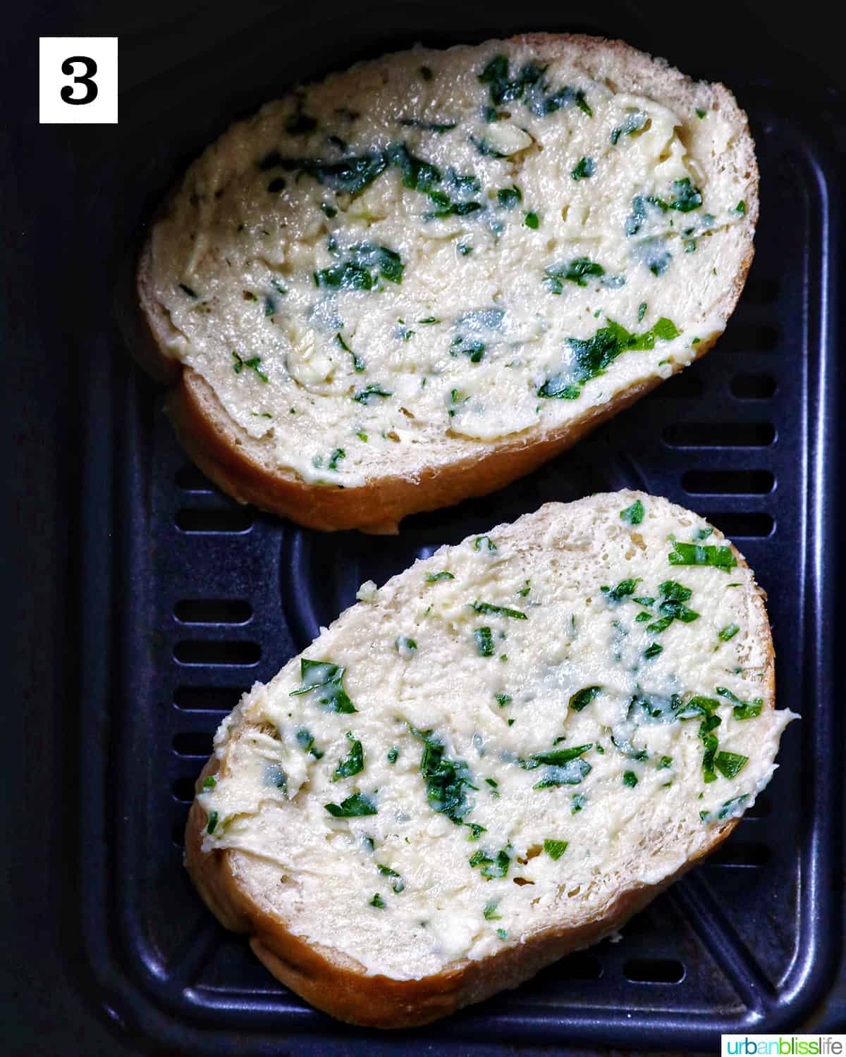 two slices of garlic bread in an air fryer basket.