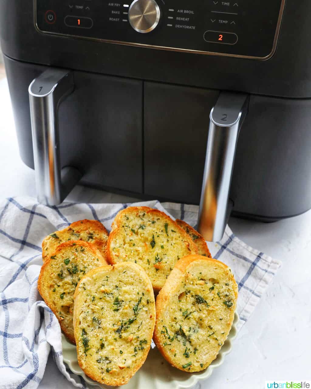 plate of garlic bread slices in front of a Ninja Foodi air fryer.