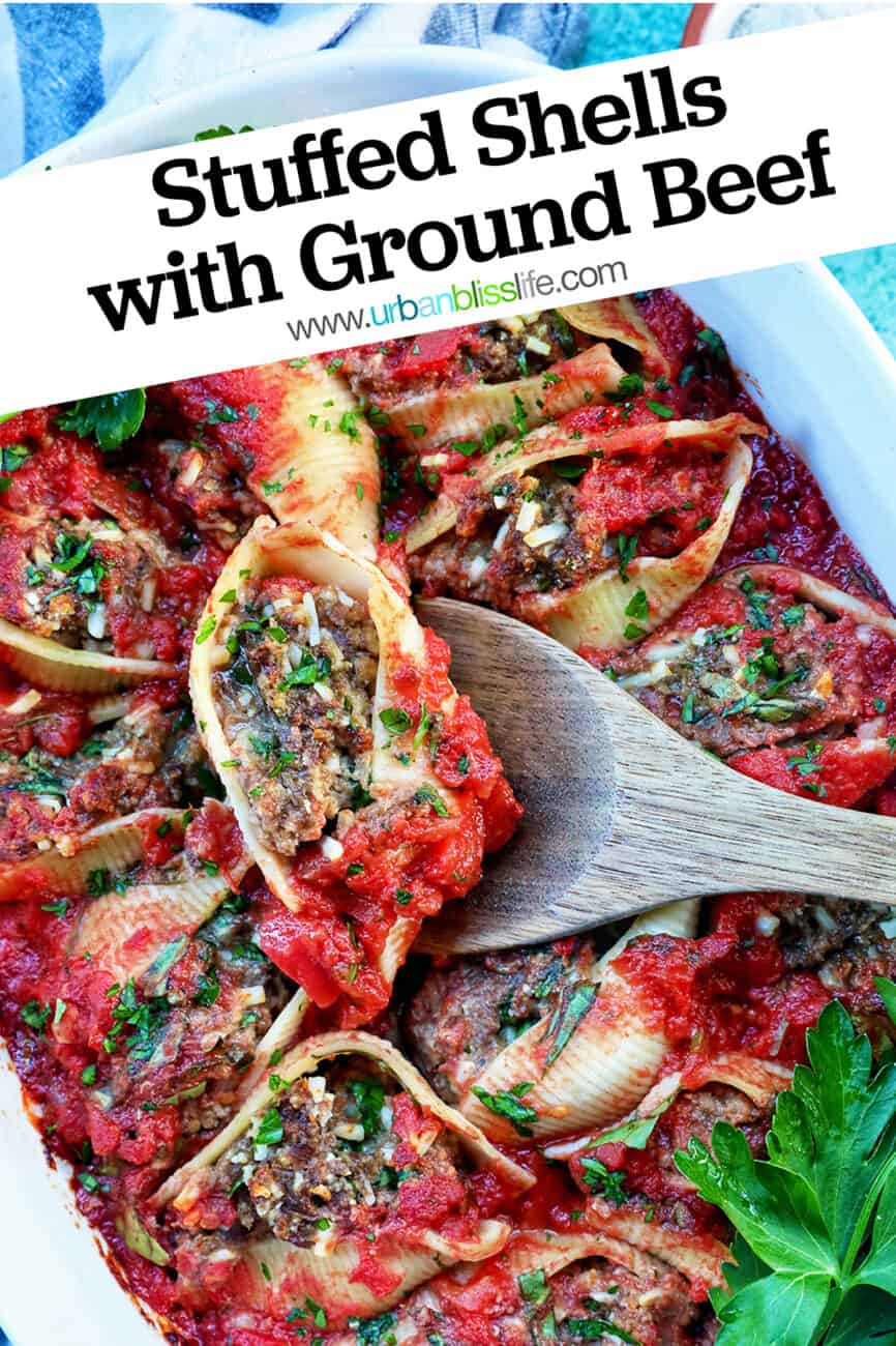 wooden spoon holding up one stuffed pasta shell above a casserole dish full of stuffed shells with ground beef and title text overlay.