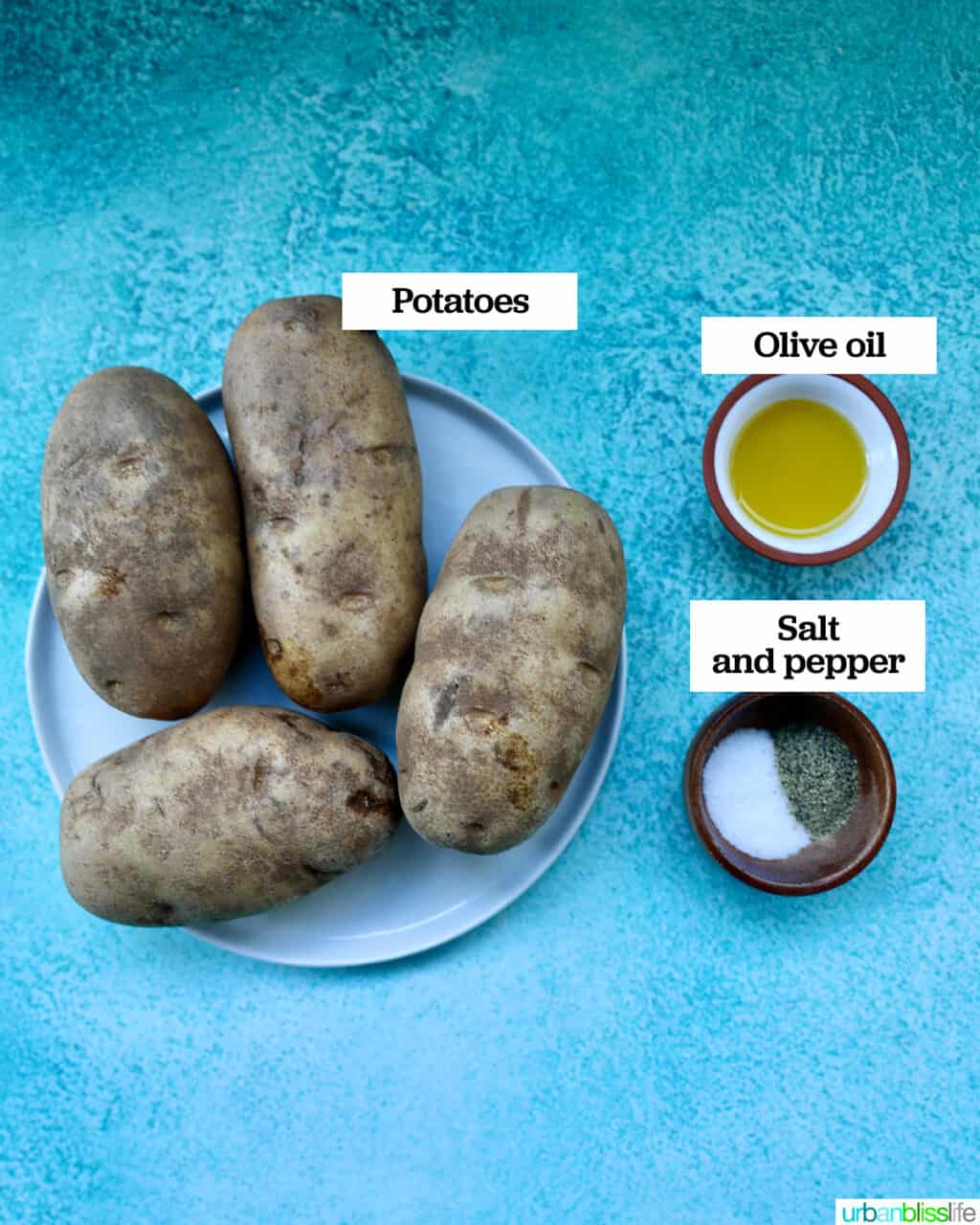 russet potatoes on a plate with bowls of olive oil and salt and pepper.