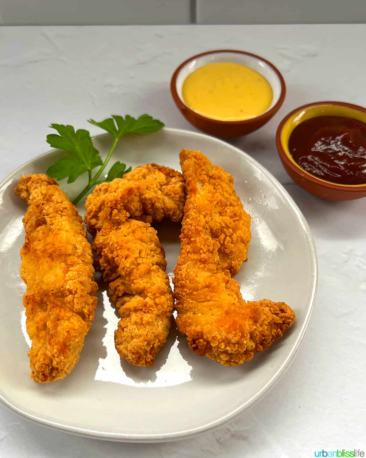 air fryer frozen chicken tenders on plate with bbq and honey mustard sauces