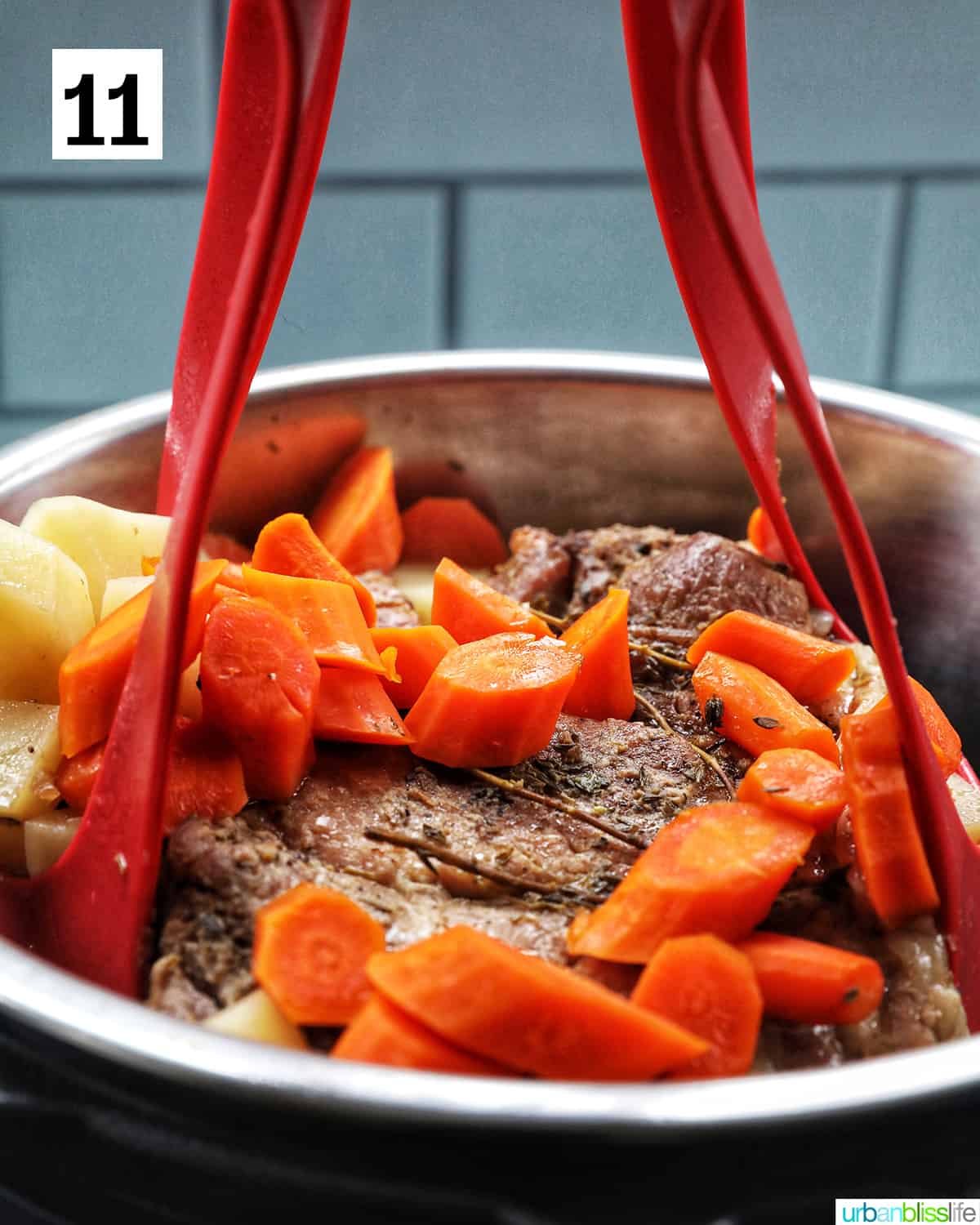 lifting the red silicone sling with pork roast, carrots, and potatoes out of the Instant Pot.