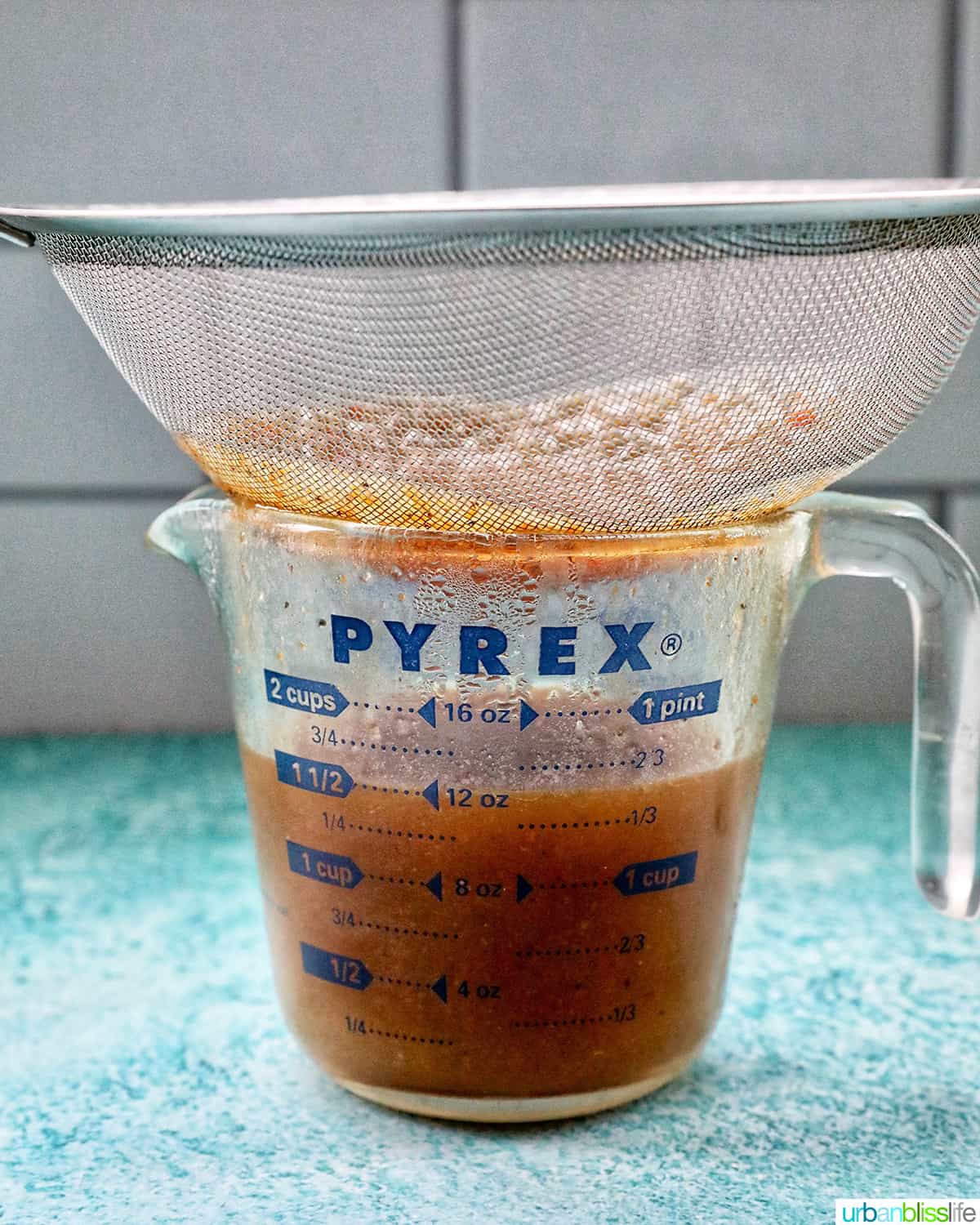 strainer straining out solids from beef drippings to make gravy.