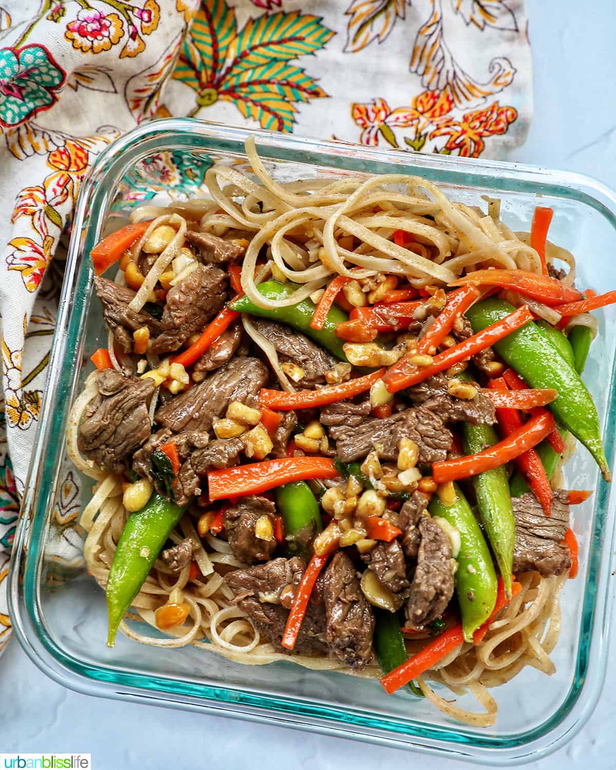 beef pad thai noodles with vegetables in a meal prep glass container.