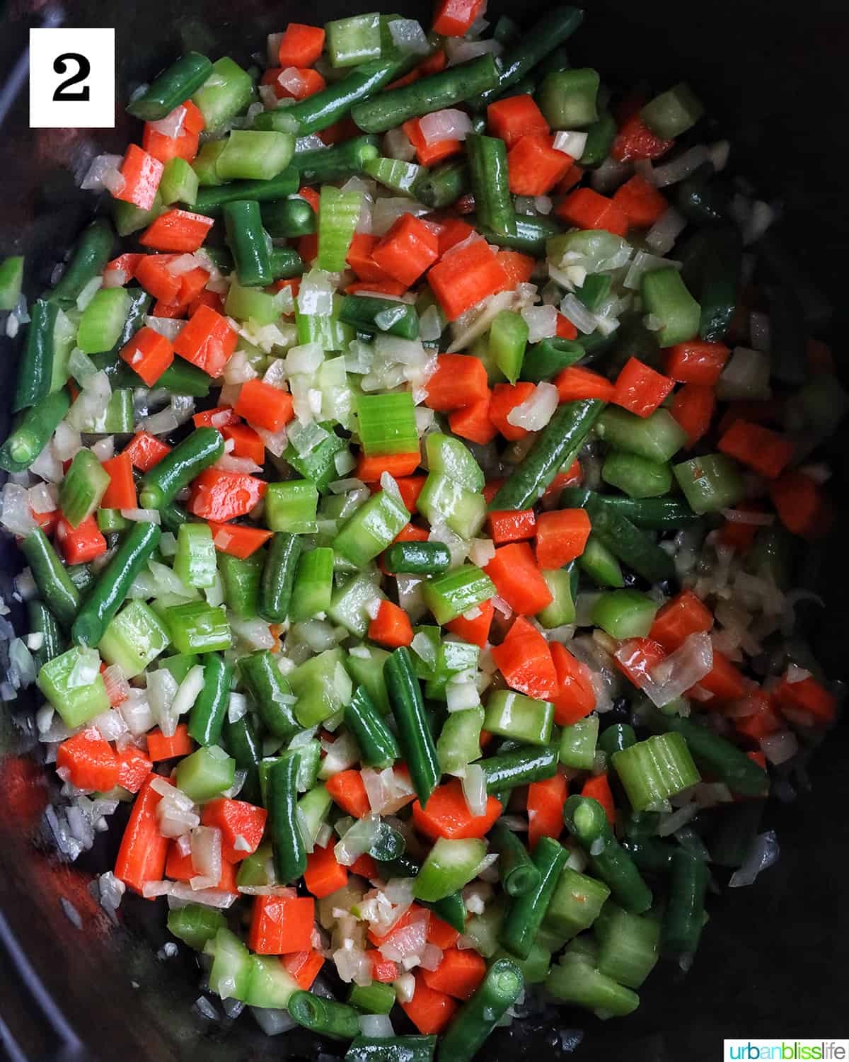 carrots, celery, onions, and green beans in a pan.