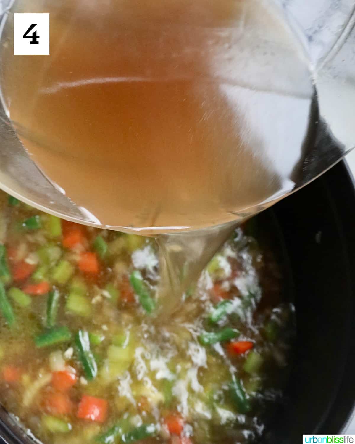 broth pouring into a pot of chicken minestrone soup.