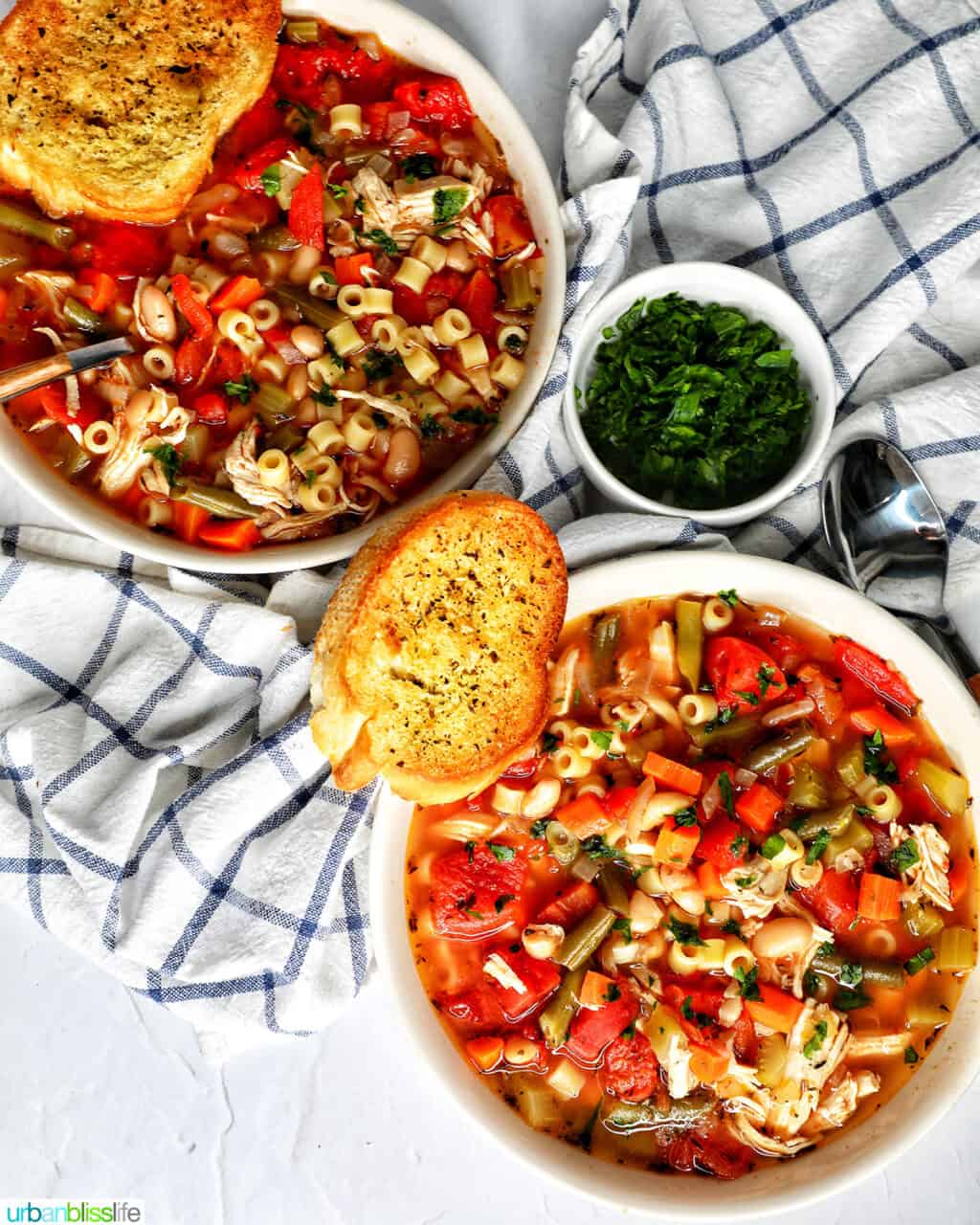 two bowls of Chicken Minestrone Soup in a with side of garlic bread.