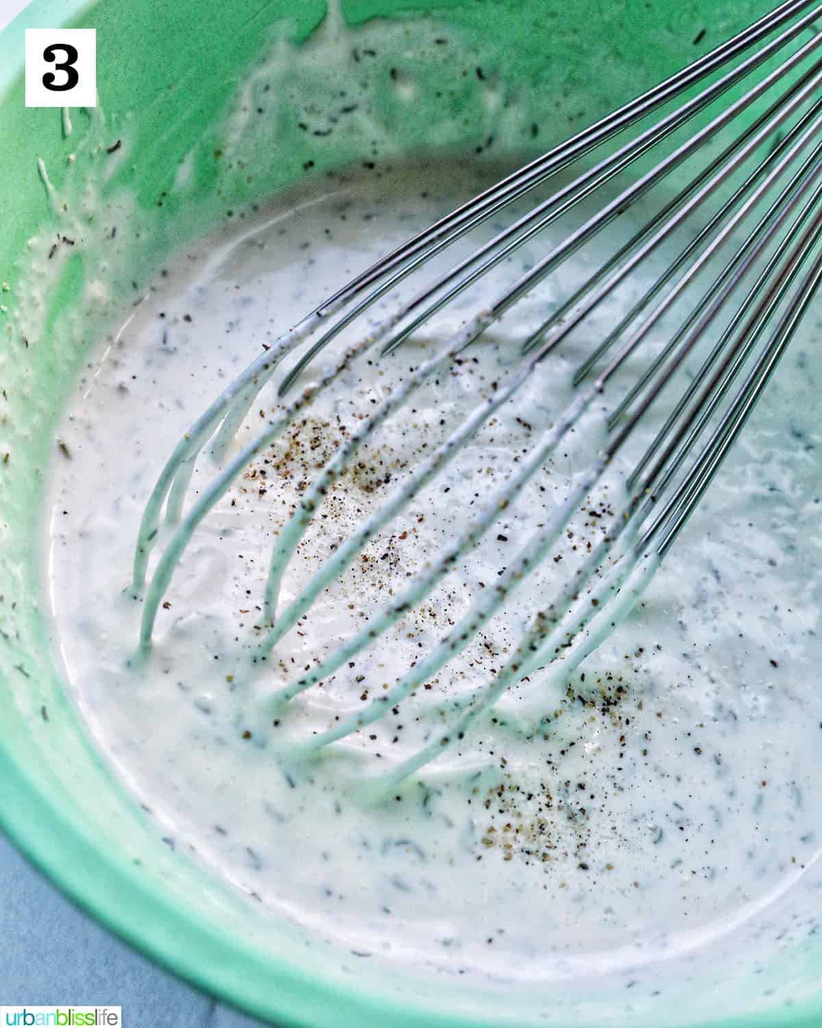 whisk in green bowl of homemade dairy free ranch dressing.