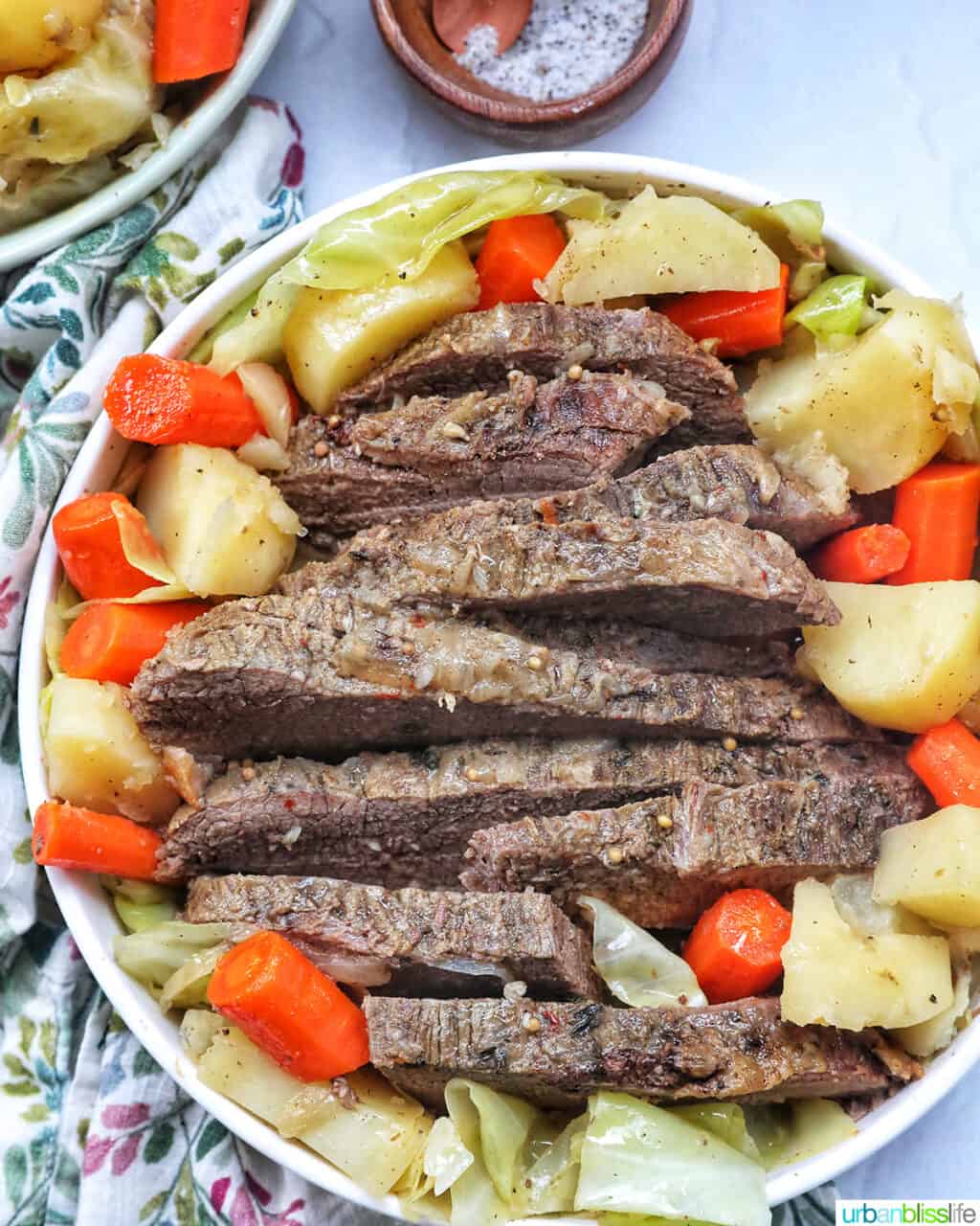 bowl of sliced dutch oven brisket with carrots, potatoes, and cabbage.