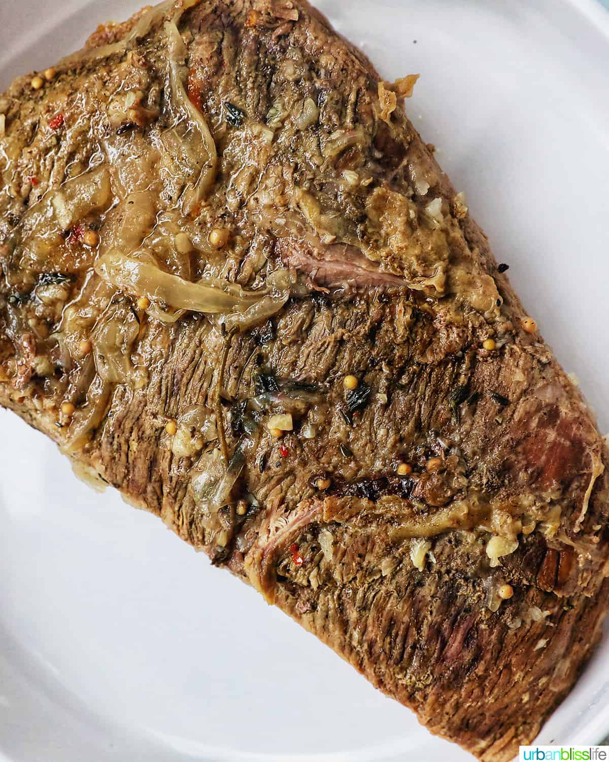 cooked brisket laying on a white plate.