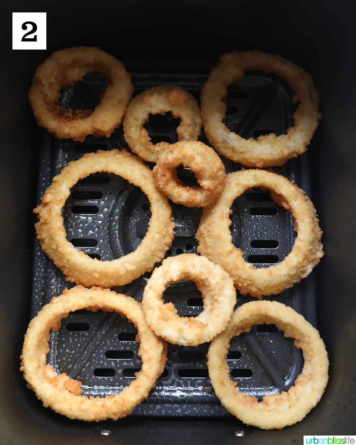 frozen onion rings in an air fryer basket.