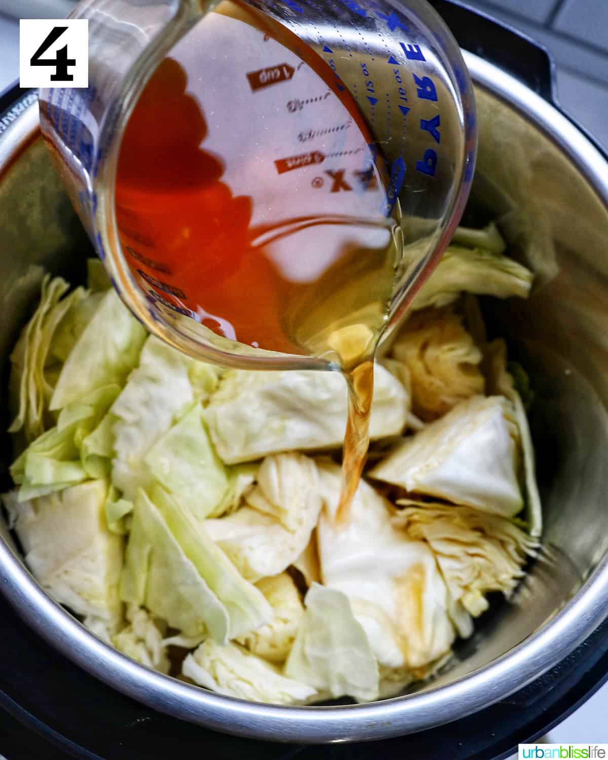 pouring vegetable broth into an instant pot with cabbage leaves.
