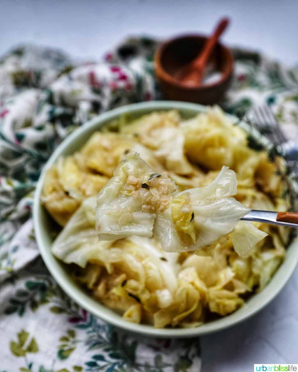 bowl of cooked instant pot cabbage with thyme sprigs and a fork.