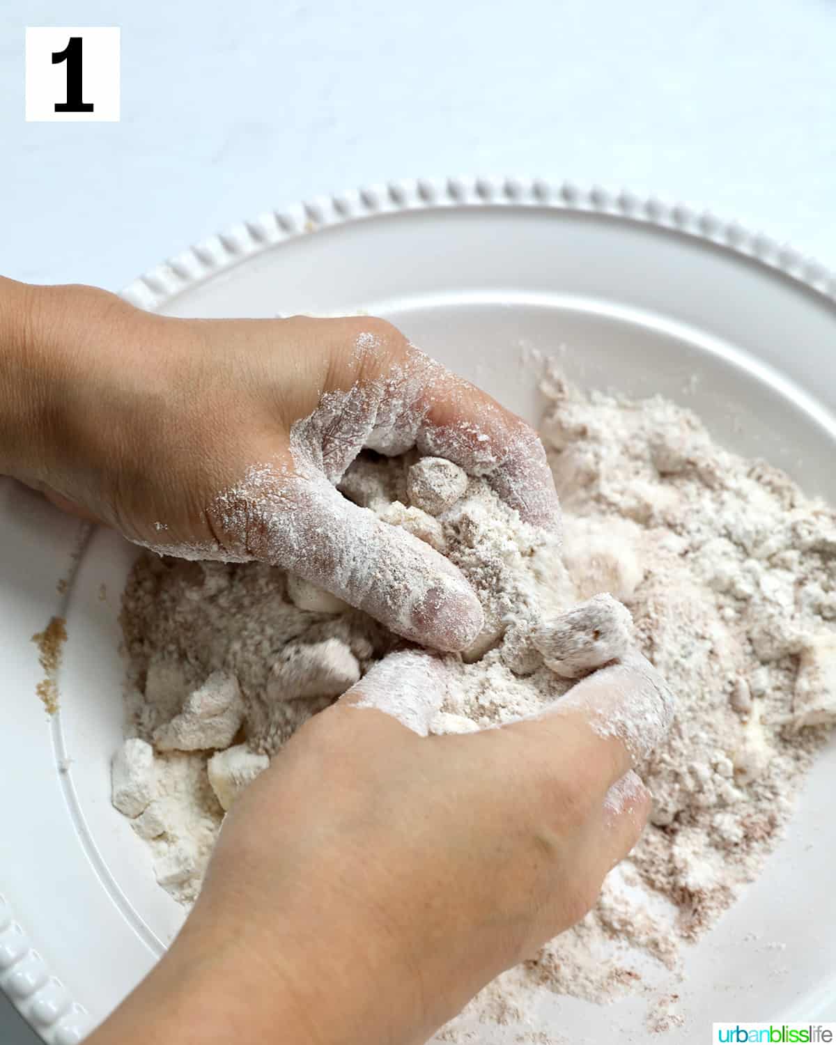 hands pressing together ingredients to make the crumb streusel topping of Irish coffee cake.