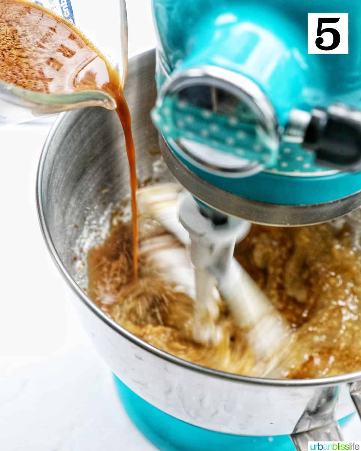 pouring in the liquid ingredients to the stand mixer to make Irish whiskey coffee cake.