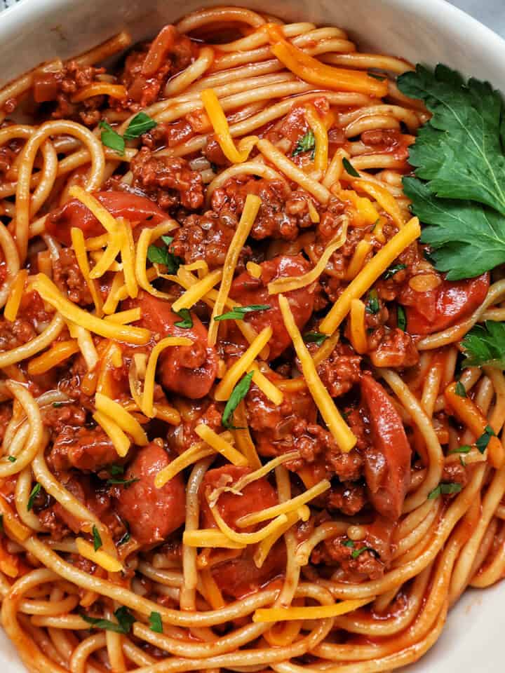 Jolibee spaghetti in a bowl with parsley, shredded cheese, and side of salt and pepper.
