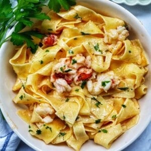 bowl of lobster pasta with side of parsley.