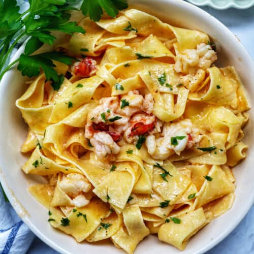 bowl of lobster pasta with side of parsley.