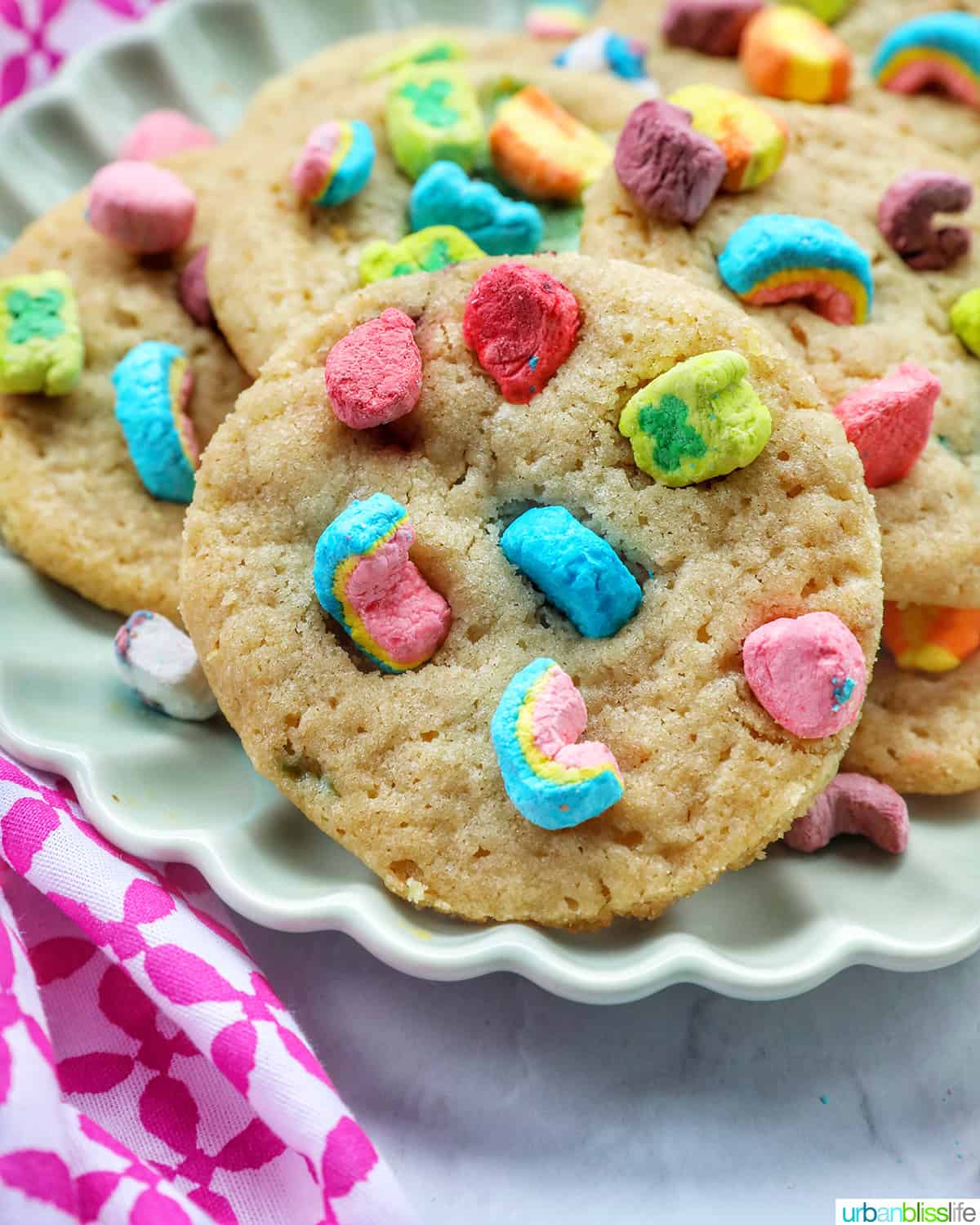 plate with several Lucky Charms cookies stacked, with colorful marshmallows on top.