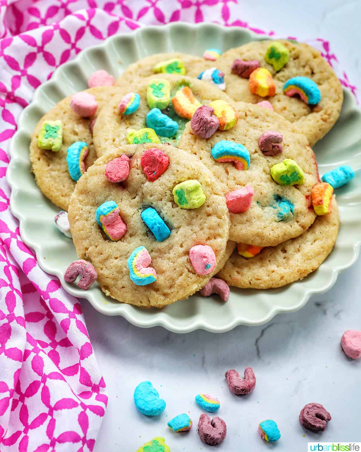 plate with several Lucky Charms cookies stacked, with colorful marshmallows on top.
