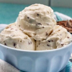 close up of bowl of stracciatella ice cream scoops with bowl of chocolate shavings on the side.