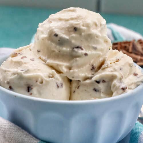 close up of bowl of stracciatella ice cream scoops with bowl of chocolate shavings on the side.