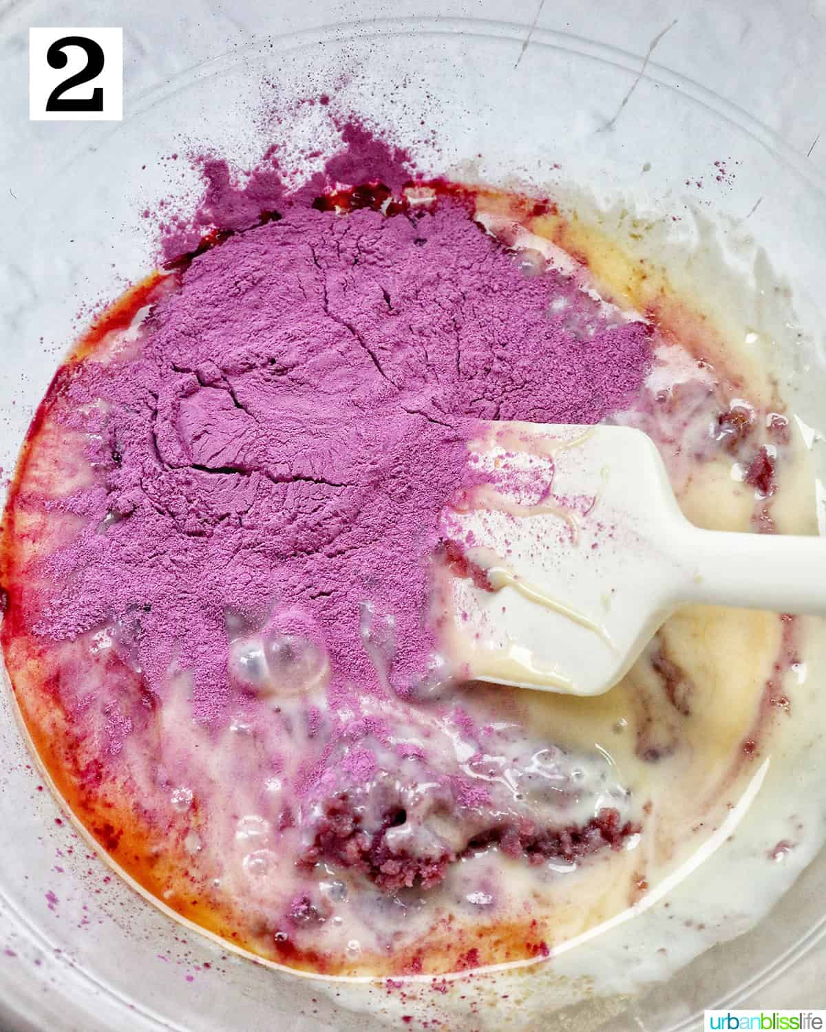 mixing together ingredient to make ube ice cream in a large bowl.