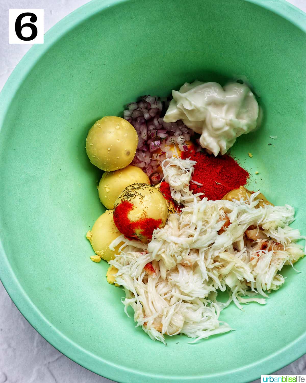 green bowl with ingredients to make crab deviled eggs.