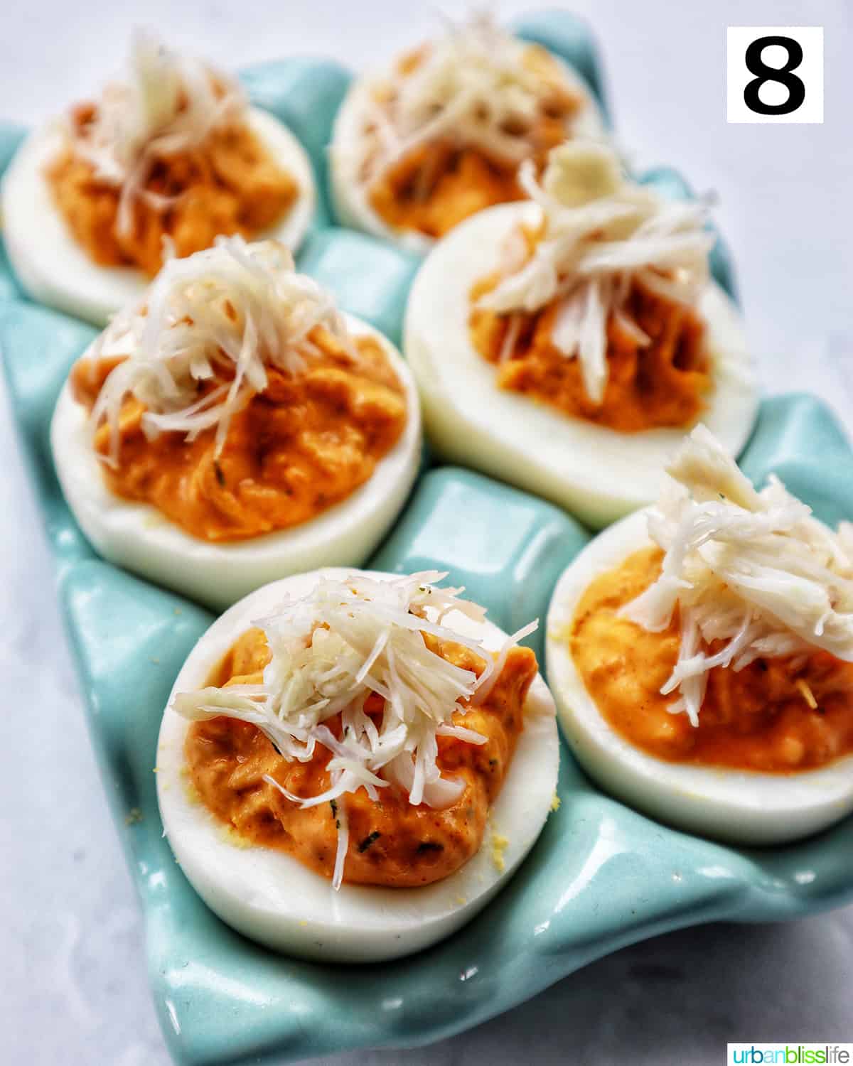 six crab deviled eggs in a blue egg holder.