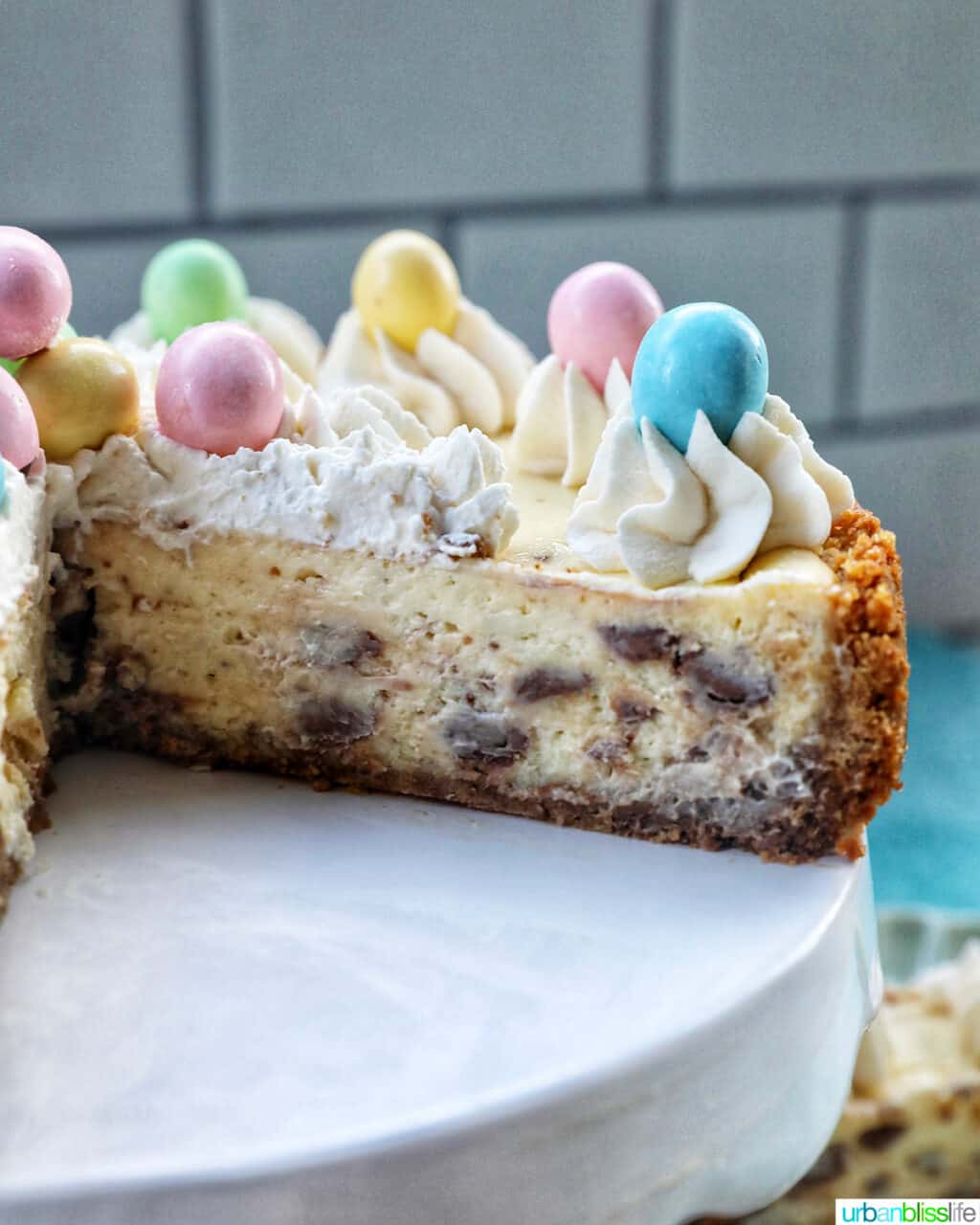 sliced easter egg cheesecake with mini chocolate eggs and whipped cream.