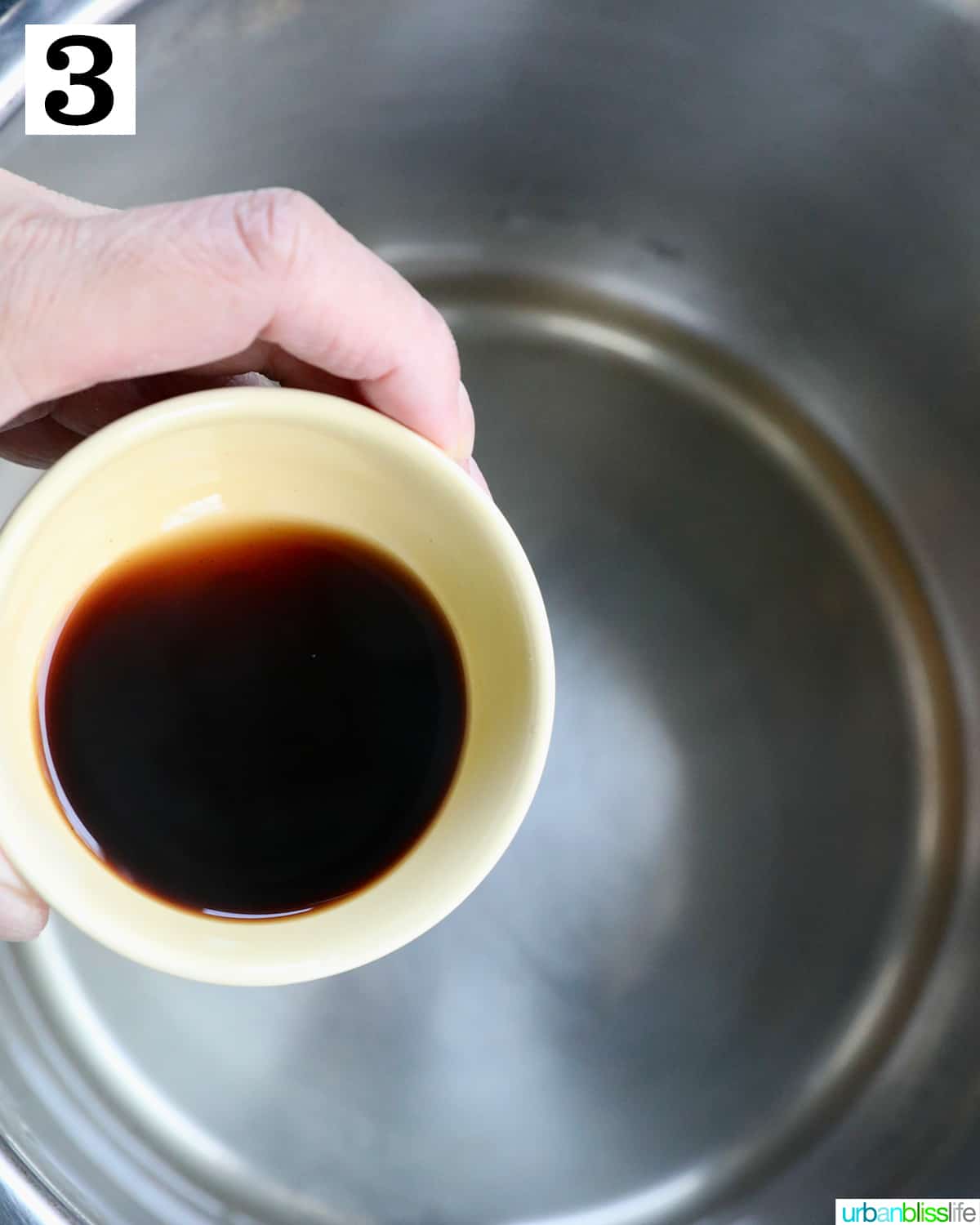 hand with sauce over an instant pot.