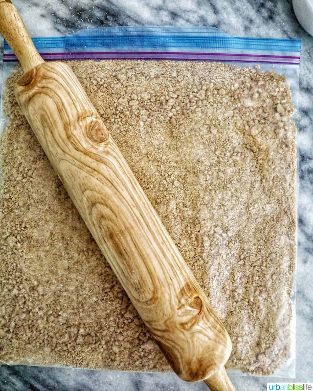 rolling pin over a plastic bag with crushed graham cracker cookies.