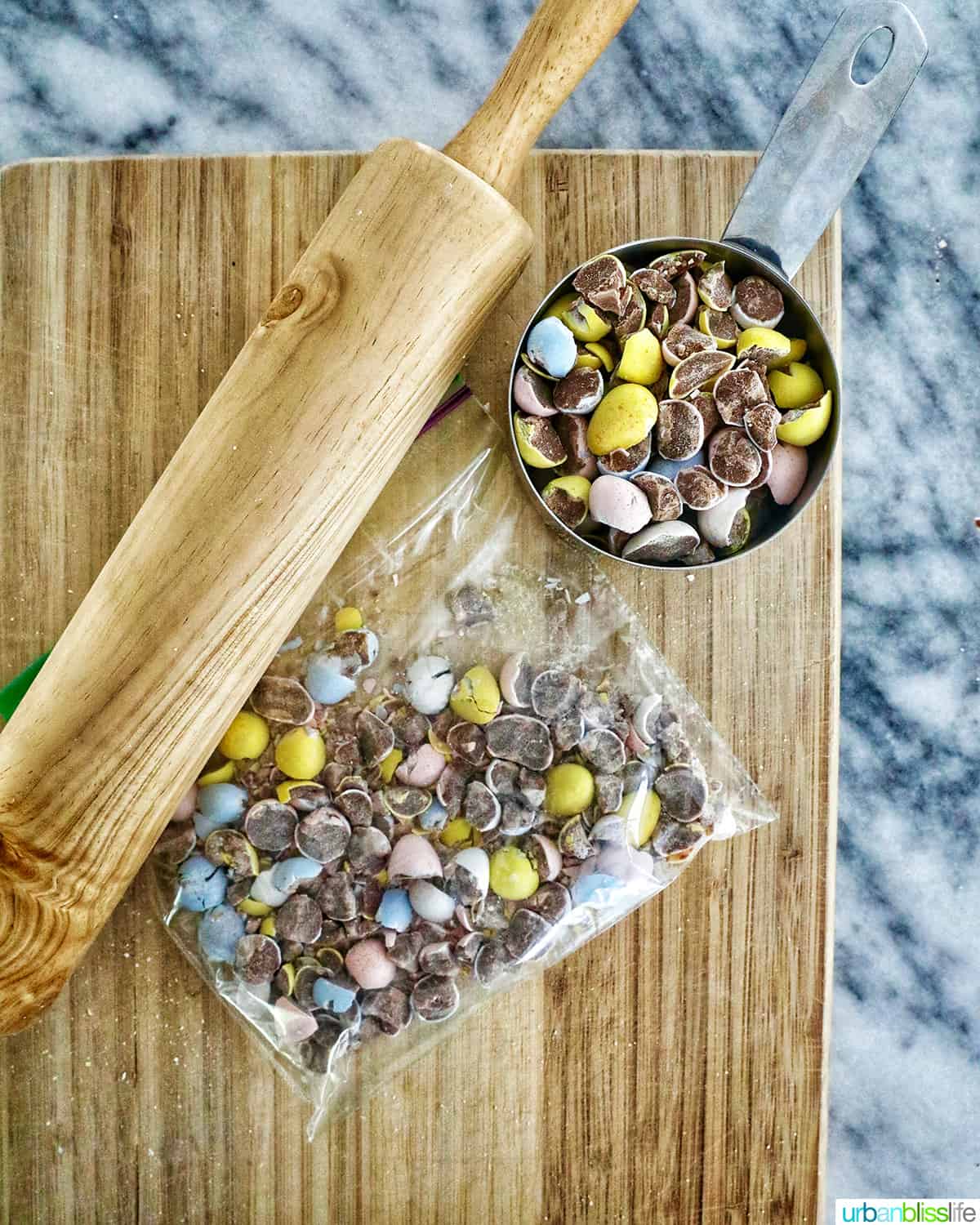 rolling pin with chopped mini chocolate eggs on a cutting board.