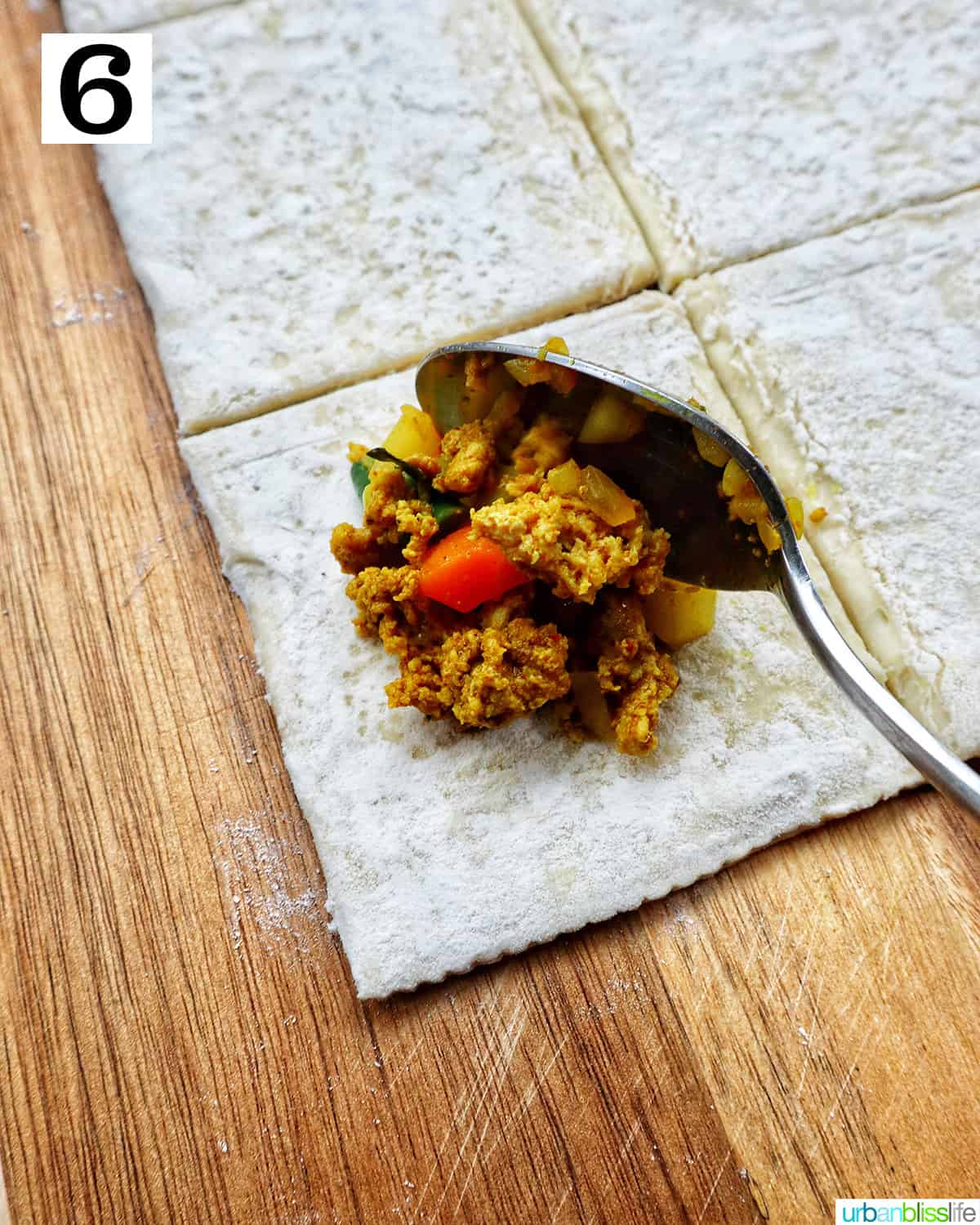 spooning curry filling onto the center of a puff pastry square on cutting board.