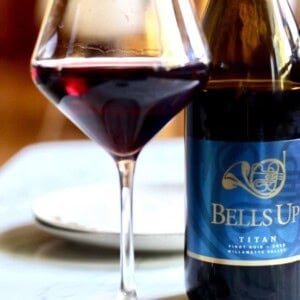 glass of red wine next to a bottle of Bells Up Winery pinot noir.