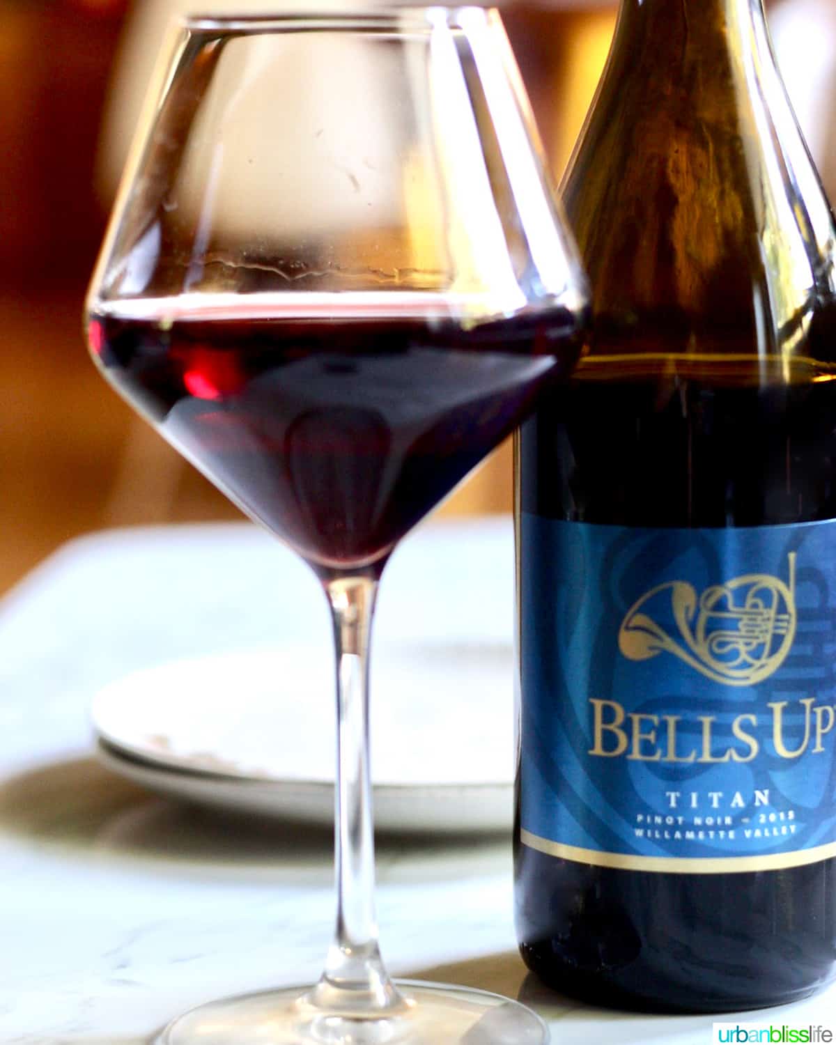 glass of red wine next to a bottle of Bells Up Winery pinot noir.